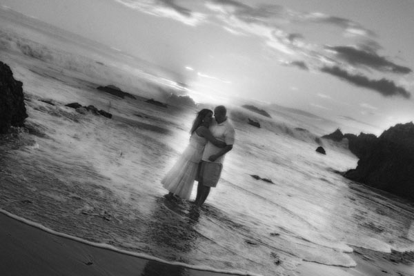 Beach engagement shots on the shores in Santa Barbara. Bride and groom are in the water with the sun breaking through the clouds.