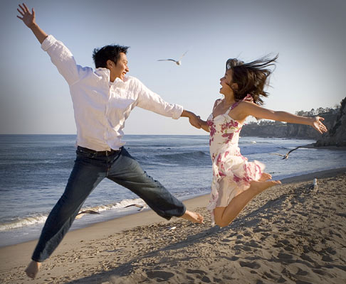 Shot of a couple who got engaged jumping in the air at Paradise Cove.