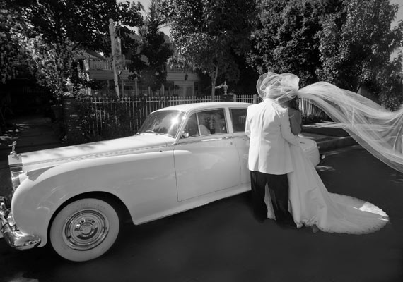 Magazine style fashion photoshoot in Los Angeles. Portrait of the Bride and Groom looking at their reflection in a Rolls Royce classic car limousine.