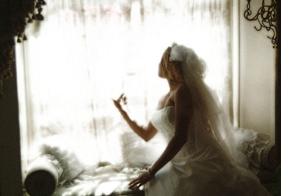 Classic window light photo of an Orange County wedding photographer as she looks outside for the groom