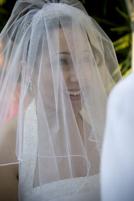 Photojournalism of a bride smiling at the groom during their vows at the ceremony.