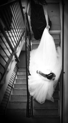 Photojournalism of a bride walking down the stairs to catch her limousine.