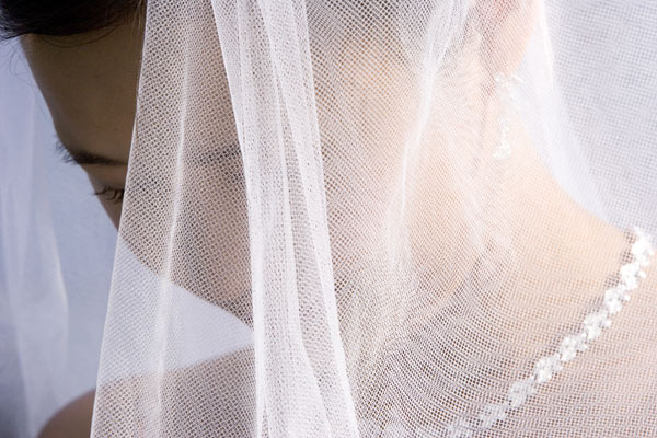 Photojournalism of a bride at the alter covered by her veil.