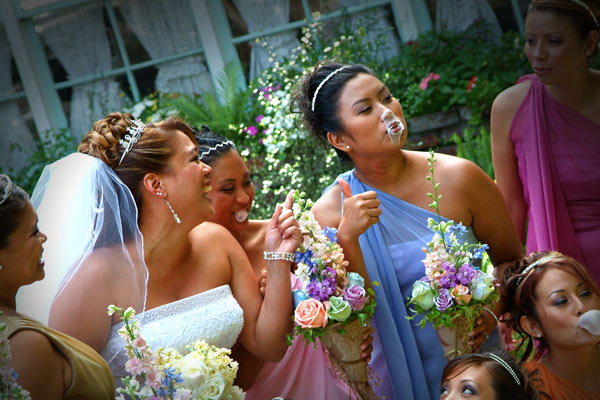Photojournalistic photo of all the bridesmaids with one popped gum on her nose.