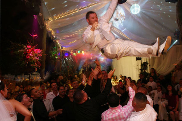 Groom get's airborn as his groomsmen toss him up in this photojournalistic shot at a Los Angeles wedding reception location.