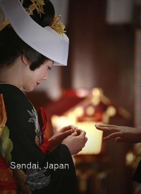 Photojournalistic photo of a wedding in Sendai, Japan. Bride is putting a ring on the grooms finger.